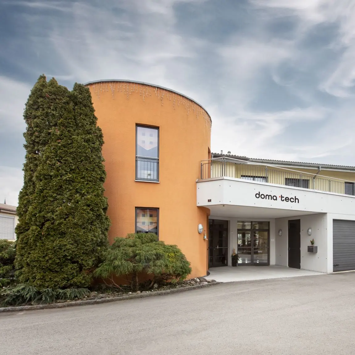 Das moderne Firmengebaeude und der Eingangsbereich der doma tech mit orangefarbenem Rundturm